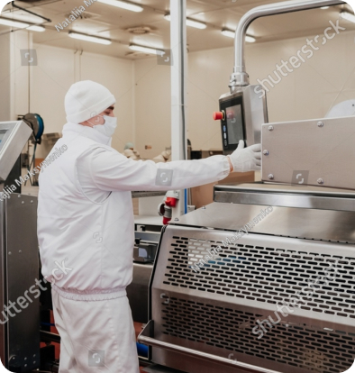 Technician in protective clothing operating production equipment in a cleanroom
