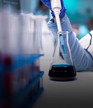 Technician pipetting liquid into a laboratory flask