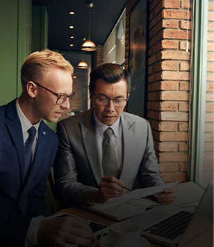 Two colleagues reviewing documents at a laptop